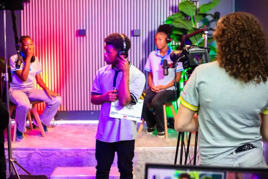 Leerlingen werken met een camera, filmklapper en microfoons aan een opname