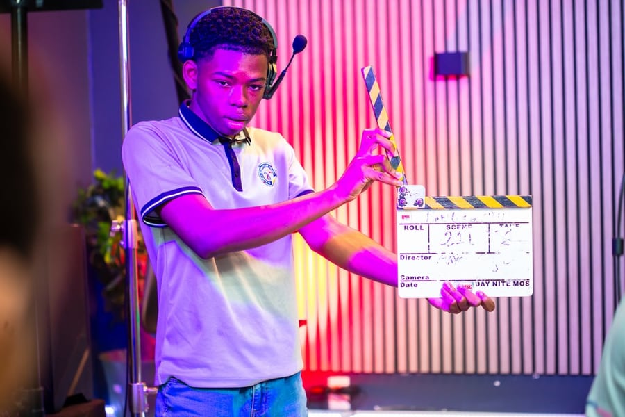 Een leerling gebruikt een filmklapper en headset in de studio